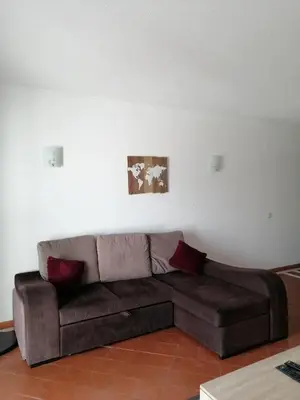 a living room with a brown couch against a white wall at apartamento em albufeira in Albufeira