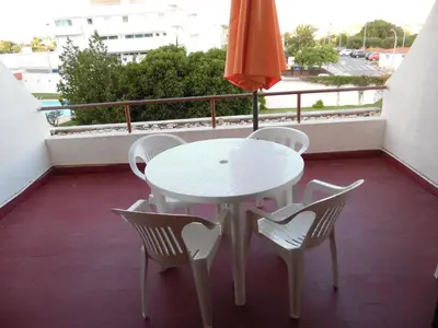 a white table and chairs on a balcony with an umbrella at apartamento em albufeira in Albufeira