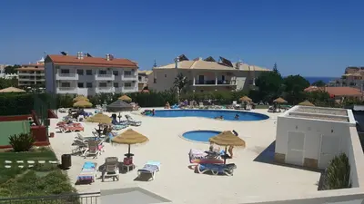 a large pool with chairs and umbrellas and people at Vista das Ondas Apartment in Albufeira