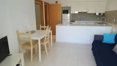 a kitchen with a counter and a table and a couch at Vista das Ondas Apartment in Albufeira