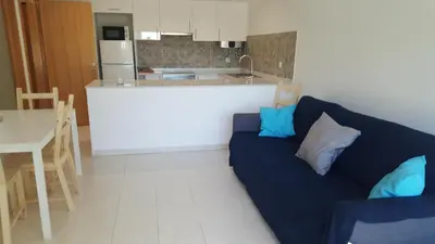 a living room with a blue couch and a kitchen at Vista das Ondas Apartment in Albufeira