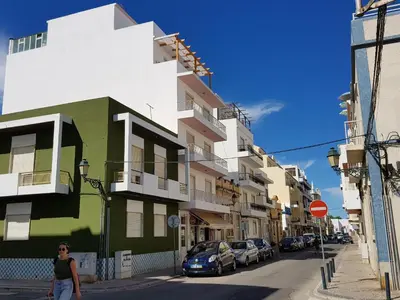 a woman walking down a city street with buildings at My Place @ Faro Ria Views in Faro