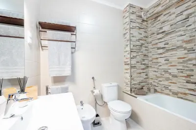 a bathroom with a white toilet and a bath tub at My Place @ Faro Ria Views in Faro