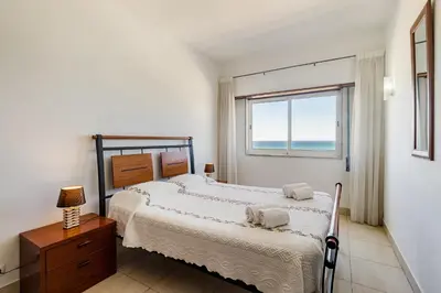 a bedroom with a bed and a window with the ocean at Torres Mira Praia by Garvetur in Quarteira