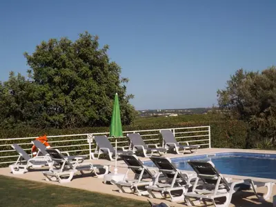 a group of lounge chairs next to a swimming pool at Villa Estrelamar in Boliqueime