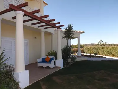 a pergola on a house with a chair under it at Villa Estrelamar in Boliqueime
