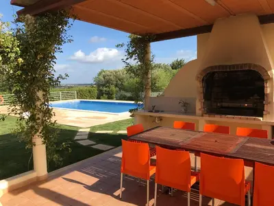 a patio with a table and chairs and a swimming pool at Villa Estrelamar in Boliqueime