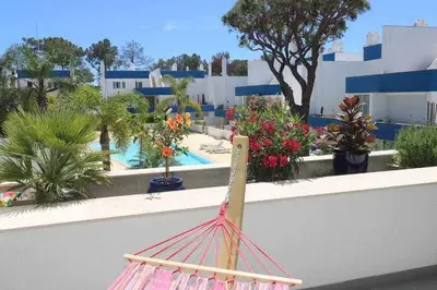 a hammock on a wall with plants and a pool at Hiva T3 By FHR in Vilamoura