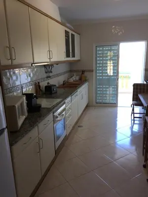 a kitchen with white cabinets and a tile floor at Moradia Galé in Guia
