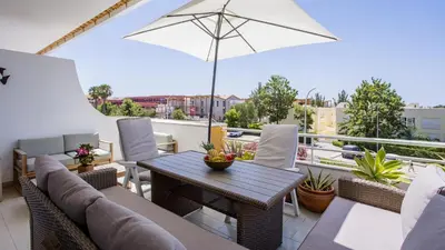 a patio with a table and chairs and an umbrella at T1 Grevilias em Vilamoura - Greice Homes in Quarteira