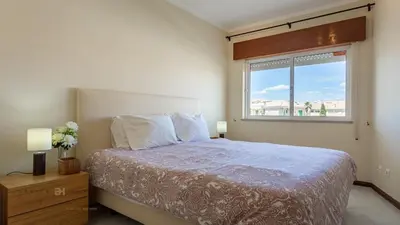 a bedroom with a large bed and a window at T1 Grevilias em Vilamoura - Greice Homes in Quarteira