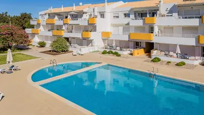 an empty swimming pool in front of a building at T1 Grevilias em Vilamoura - Greice Homes in Quarteira