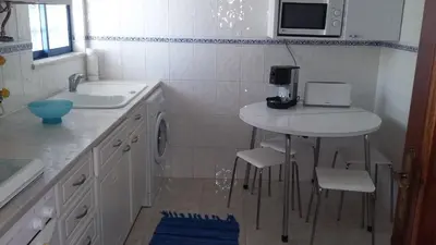 a small kitchen with a sink and a table with chairs at Quarteira T1 - Oceanides in Quarteira