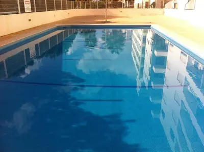 a swimming pool with blue water in a building at Quarteira T1 - Oceanides in Quarteira