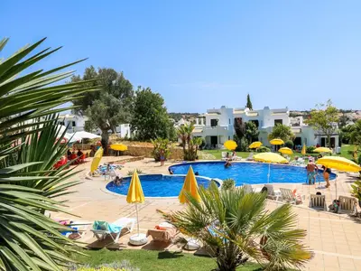 a swimming pool with chairs and umbrellas in a resort at Luxury 3 Bedroom Apartment, Albufeira Resort in Albufeira
