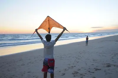 a man holding up a kite on the beach at Faro Beach House in Faro