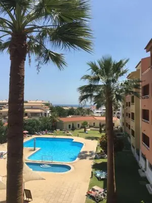 a swimming pool with palm trees in a resort at Belavista Apartment in Albufeira