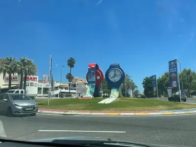 a car driving down a road with a clock sculpture at Belavista Apartment in Albufeira