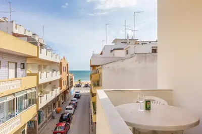 a balcony with a table and a view of a street at Apartamentos Arcada in Quarteira