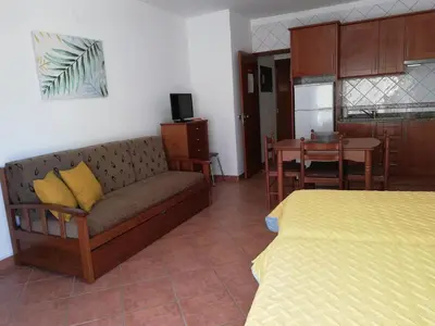 a living room with a couch and a table and a kitchen at Apartamentos Arcada in Quarteira