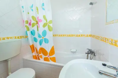 a bathroom with a toilet and a sink and a shower curtain at Apartamentos Arcada in Quarteira