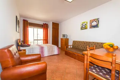 a bedroom with a couch and a bed and a table at Apartamentos Arcada in Quarteira