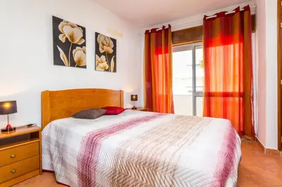 a bedroom with a bed and a window at Apartamentos Arcada in Quarteira