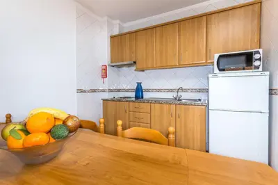 a kitchen with a table with a bowl of fruit at Apartamentos Arcada in Quarteira