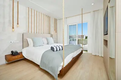 a bedroom with a swinging bed and a large window at Areias Senses in Albufeira