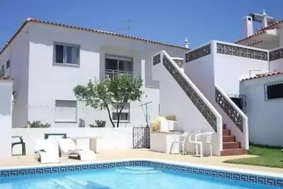 a villa with a swimming pool in front of a house at Areias Senses in Albufeira