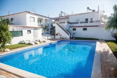 a large blue swimming pool in front of a house at Areias Senses in Albufeira