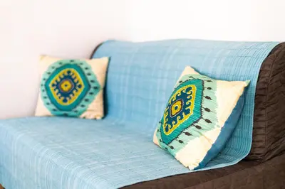 a blue couch with two pillows on it at Apartamento Mar in Quarteira