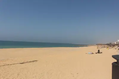 a beach with people laying on the sand and the ocean at Apartamento Mar in Quarteira