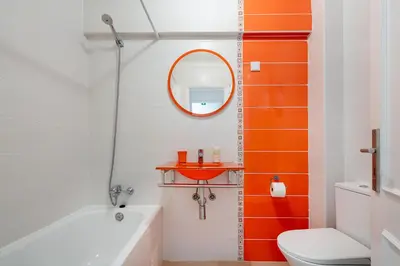 an orange and white bathroom with a toilet and a mirror at Apartamento Mar in Quarteira