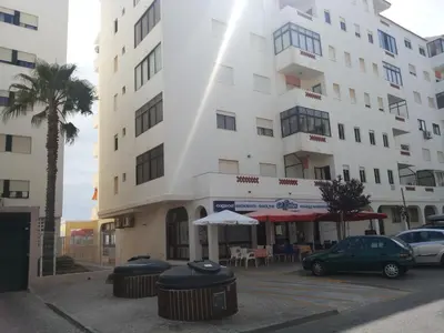 a large white building with two trash cans in front of it at Regueiró Quarteira Beach Apartment in Quarteira