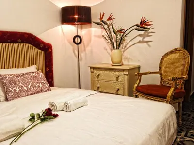a bedroom with a bed with a dresser and a chair at Vila Algarvia Boutique & Suites in Albufeira