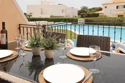 a table with plates and wine glasses on a balcony at House F São Rafael Beach - Free Wifi & Airco, NETFLIX ready - 300m from the beach in Albufeira