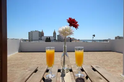 a table with two glasses of orange juice and a vase with a flower at Carmo Twenties Apartment in Faro