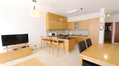 a kitchen with wooden cabinets and a table with chairs at Terraços do Mar 46- Clever Details in Vilamoura