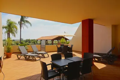 a patio with tables and chairs and an umbrella at Golf Mar Village - Clever Details in Vilamoura