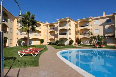 a large apartment building with a swimming pool and lounge chairs at Praia Village 104 - Clever Details in Vilamoura