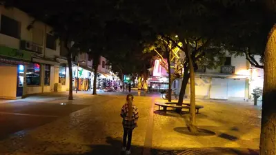 a person standing on a city street at night at Old town in Albufeira