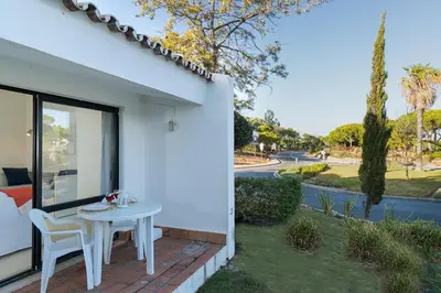 a patio with a table and chairs on the side of a house at BmyGuest - Quinta do Lago Mezzanine Apartment in Almancil