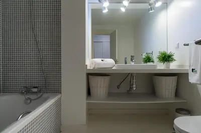 a bathroom with a sink and a tub and a mirror at BmyGuest - Quinta do Lago Mezzanine Apartment in Almancil