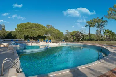 a swimming pool with blue water in a park at BmyGuest - Quinta do Lago Mezzanine Apartment in Almancil
