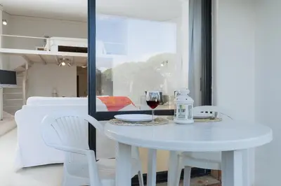 a white table with white chairs and a glass of wine at BmyGuest - Quinta do Lago Mezzanine Apartment in Almancil