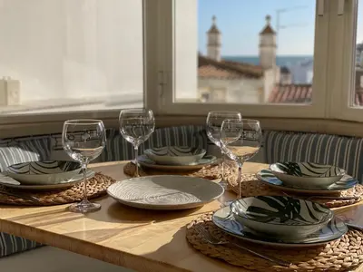 a wooden table with plates and wine glasses on it at Ocean Balcony apartment terrace sea view and pool in Albufeira