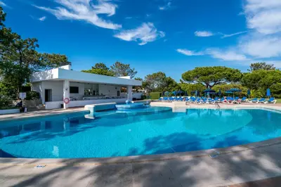 a swimming pool with chairs and a building at BmyGuest - Quinta do Lago Terrace Apartment I in Quinta do Lago