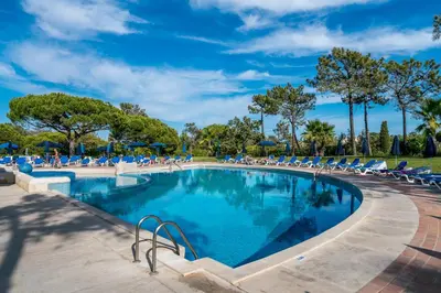 a large swimming pool with lounge chairs and trees at BmyGuest - Quinta do Lago Terrace Apartment I in Quinta do Lago