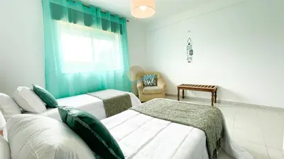 a room with two beds and a window and a chair at Vila Ricardo by Sunny Deluxe in Albufeira